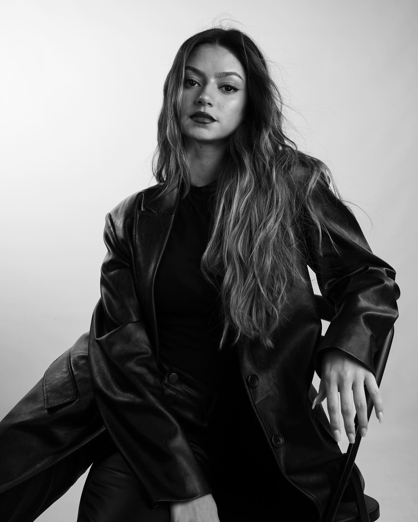 Black-and-white portrait of @lsacino seated in a leather coat