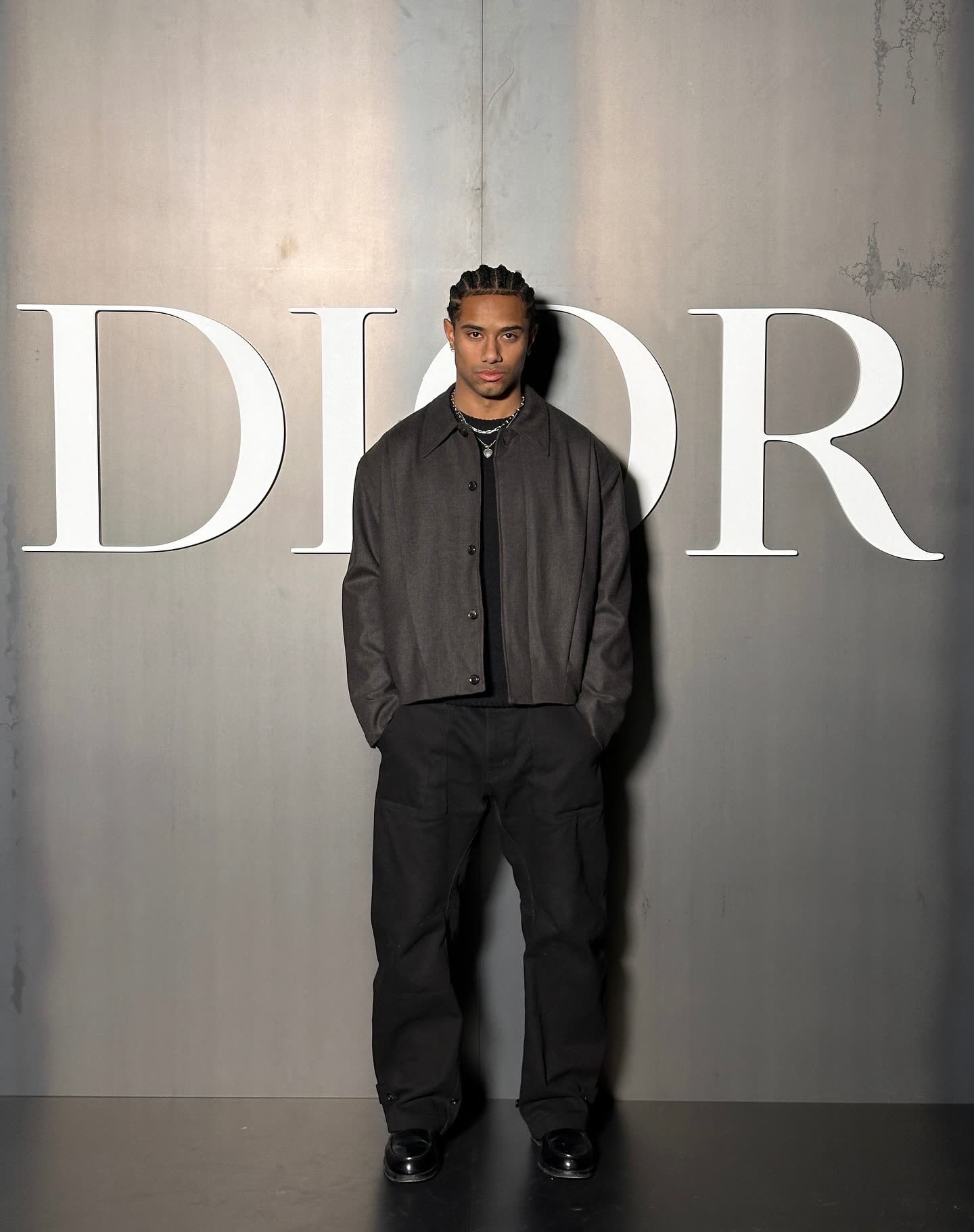 @naswyn posing in front of the Dior logo wall