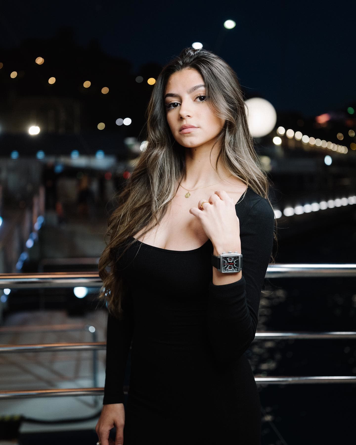 @lsacino in a black dress wearing a TAG Heuer watch at night