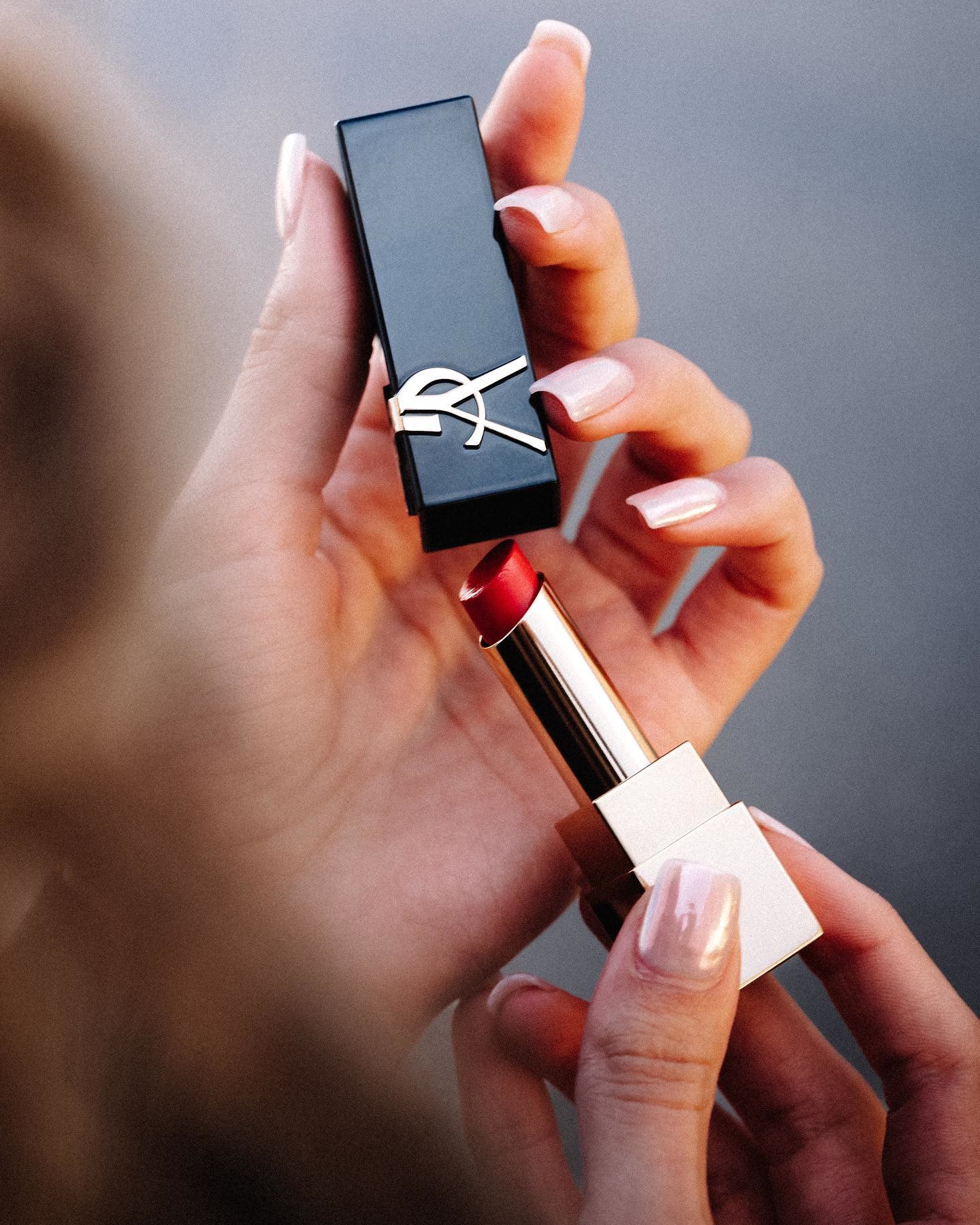 Close-up of hands opening a YSL lipstick